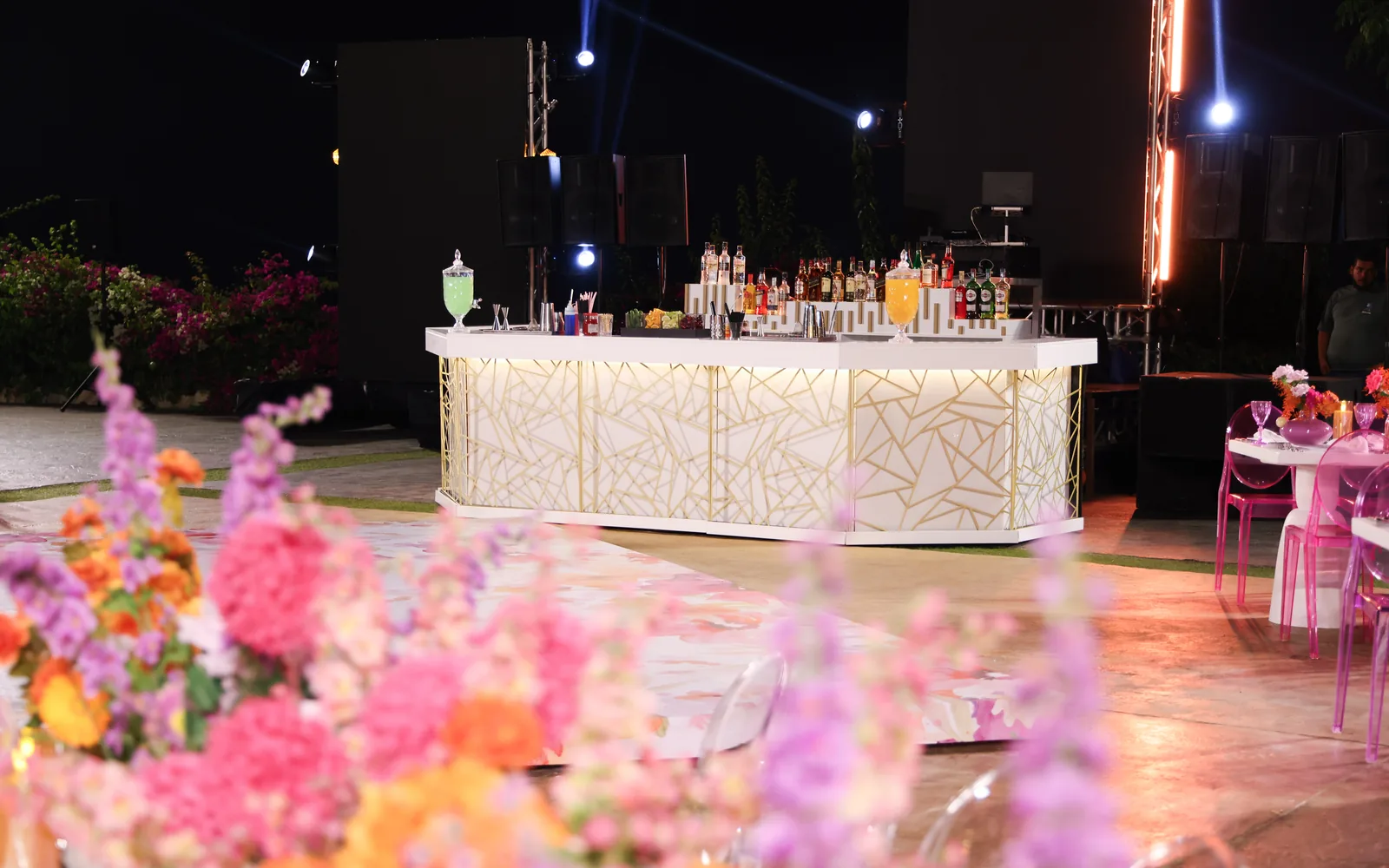 The Geometric Bar by Malabar: a white counter with a gold geometric lattice front, framed by flowers