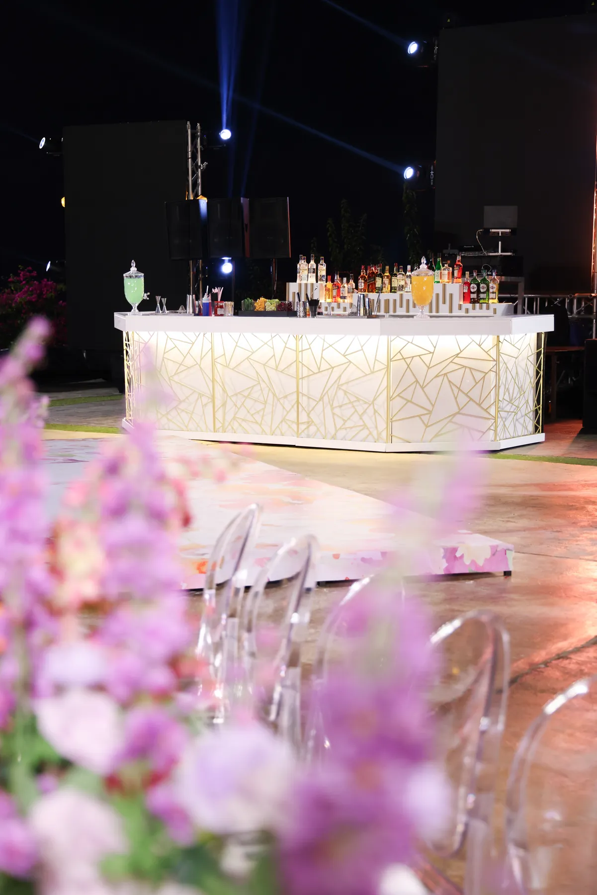 A portrait view of the Geometric Bar at a night reception, framed by pink flowers