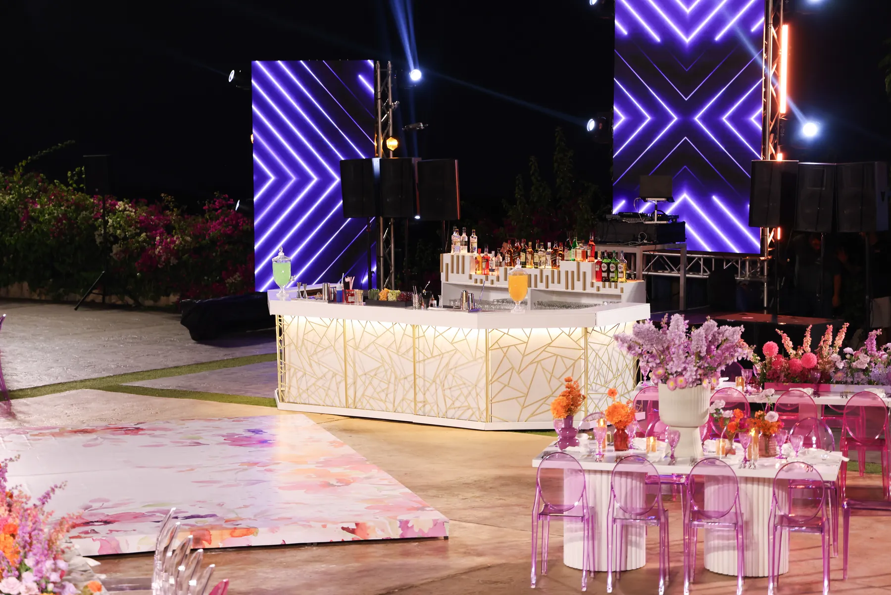 Wide view of the Geometric Bar and flower-lined reception tables at night