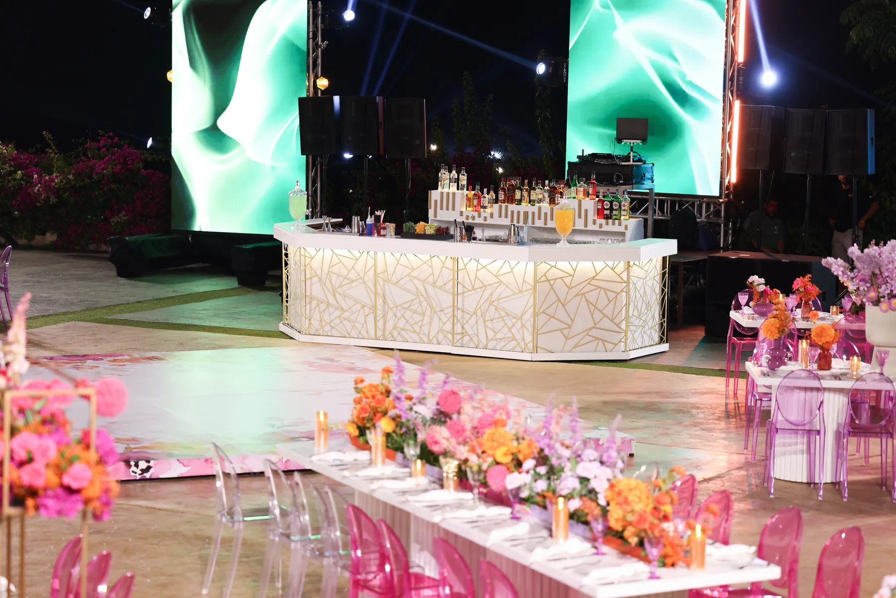 The Geometric Bar surrounded by bright floral tables at an evening reception