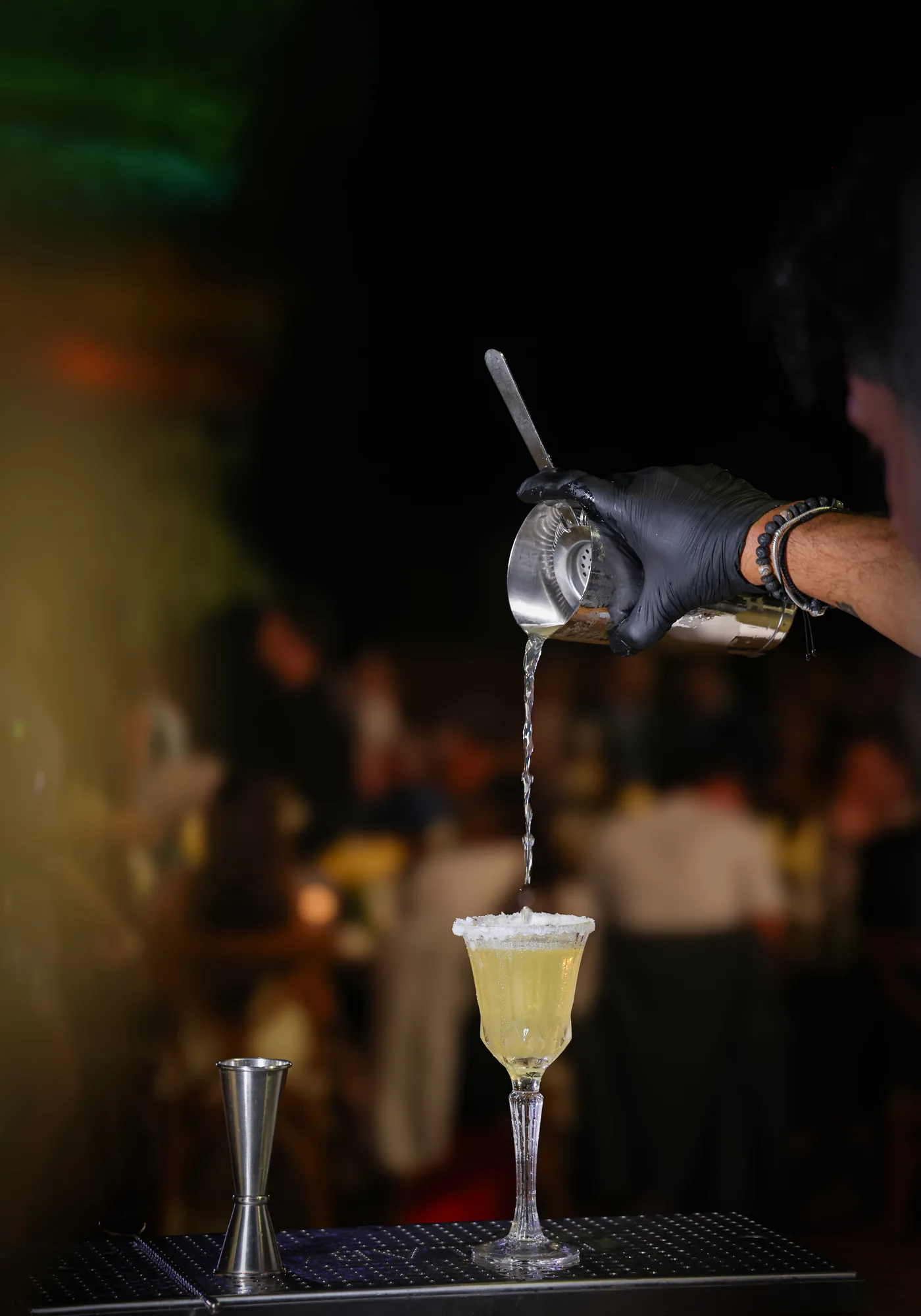 A bartender straining a freshly made cocktail into a coupe glass