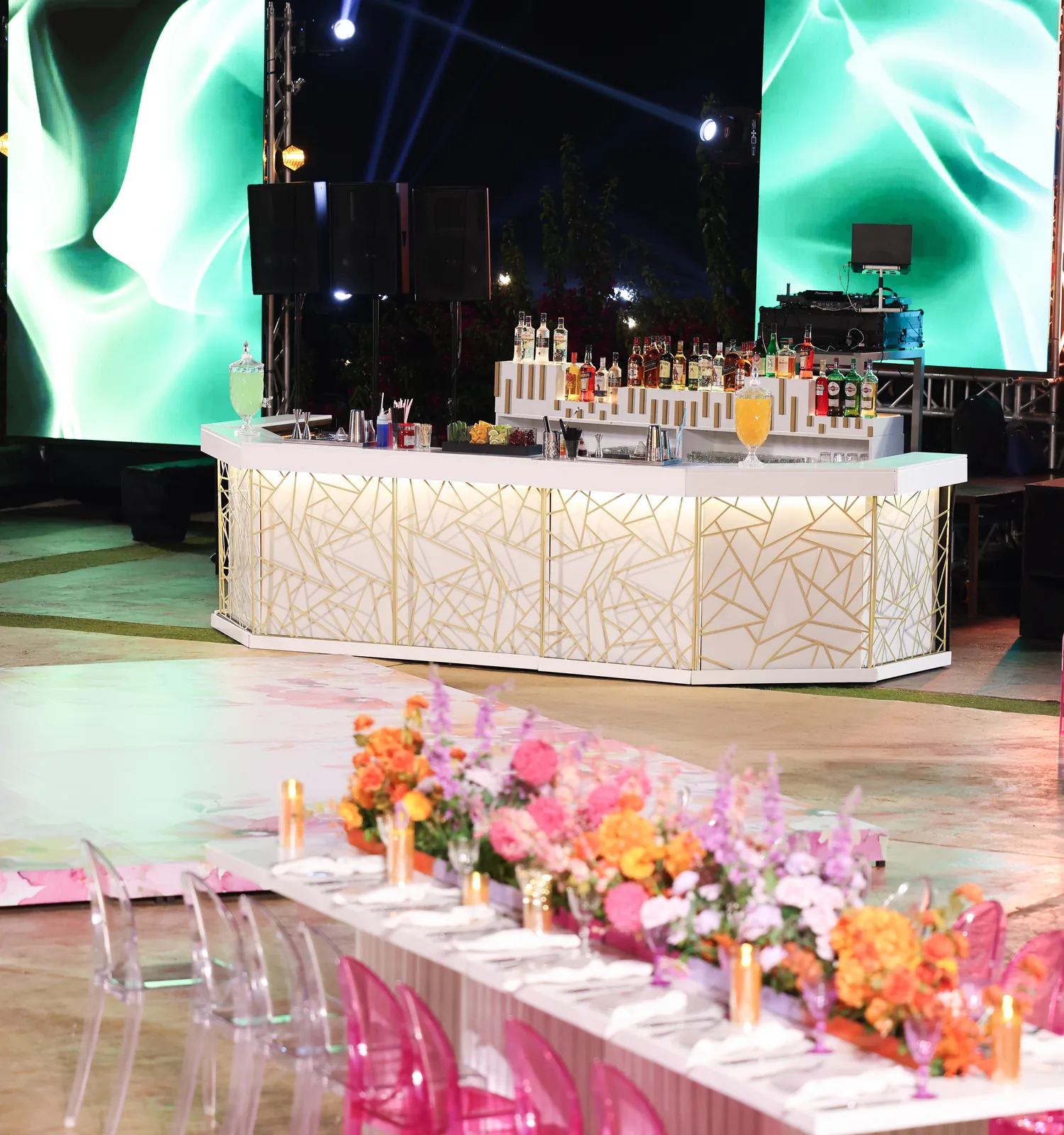 A Malabar bar and fully dressed banquet tables with floral runners at an evening reception