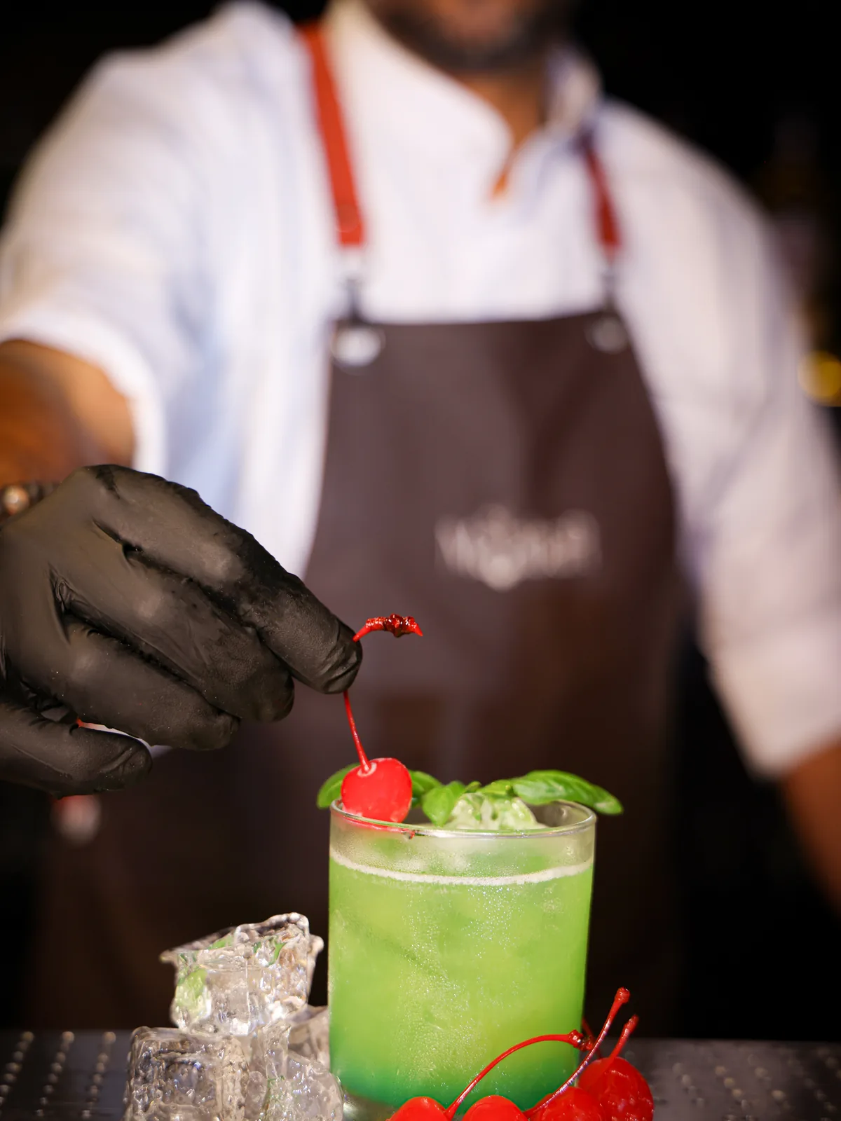 A Malabar bartender in a branded apron garnishing a cocktail behind the bar
