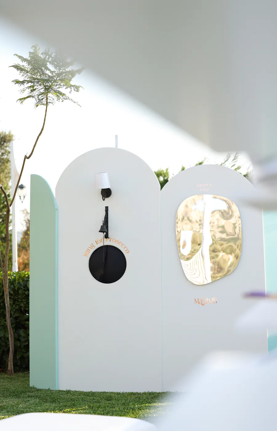 The Ambiance welcome station: soft sage arched panels with a serving portal and gold mirror