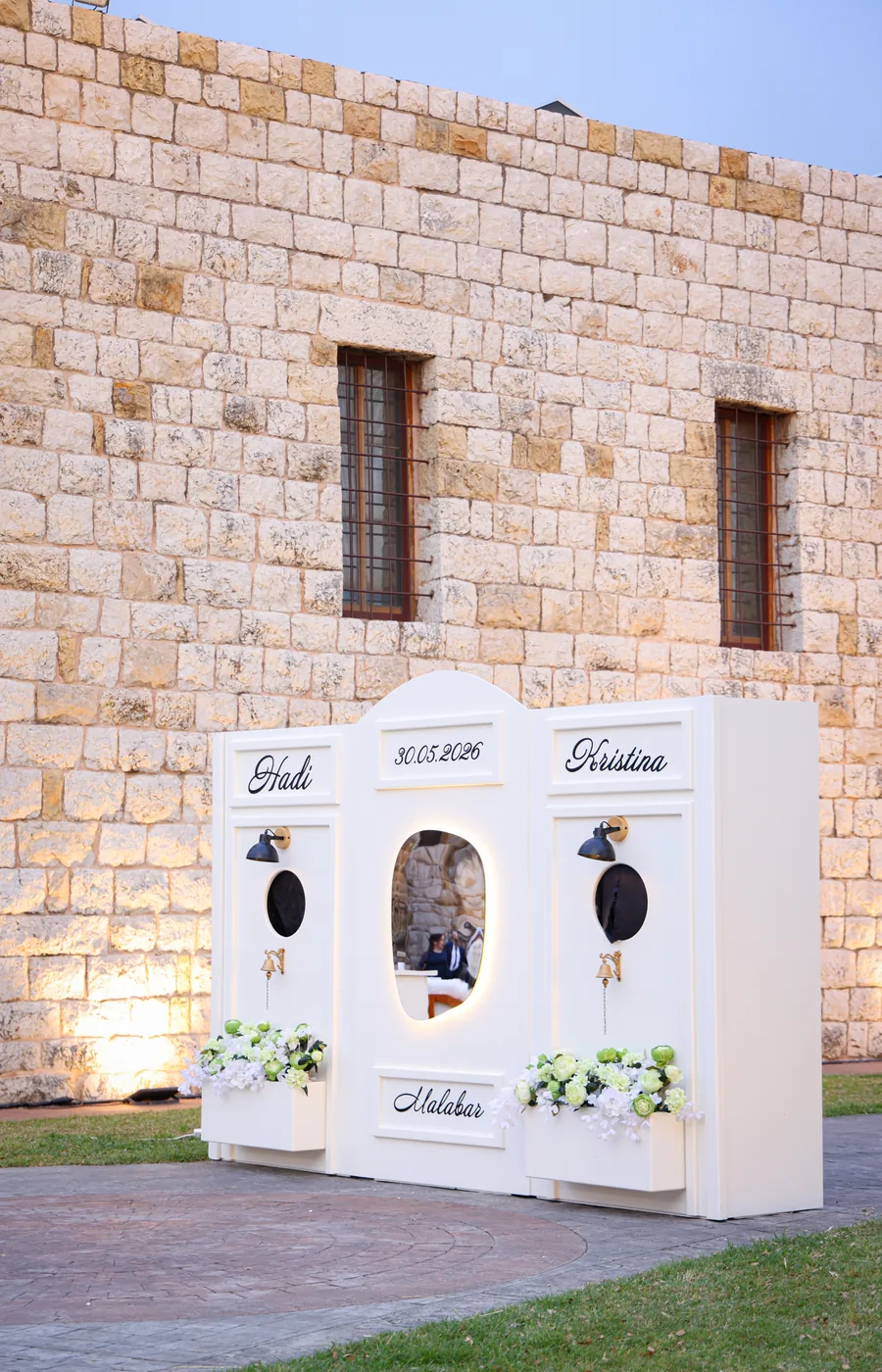 The Crème de la Crème welcome wall: a white station with arched serving windows against stonework