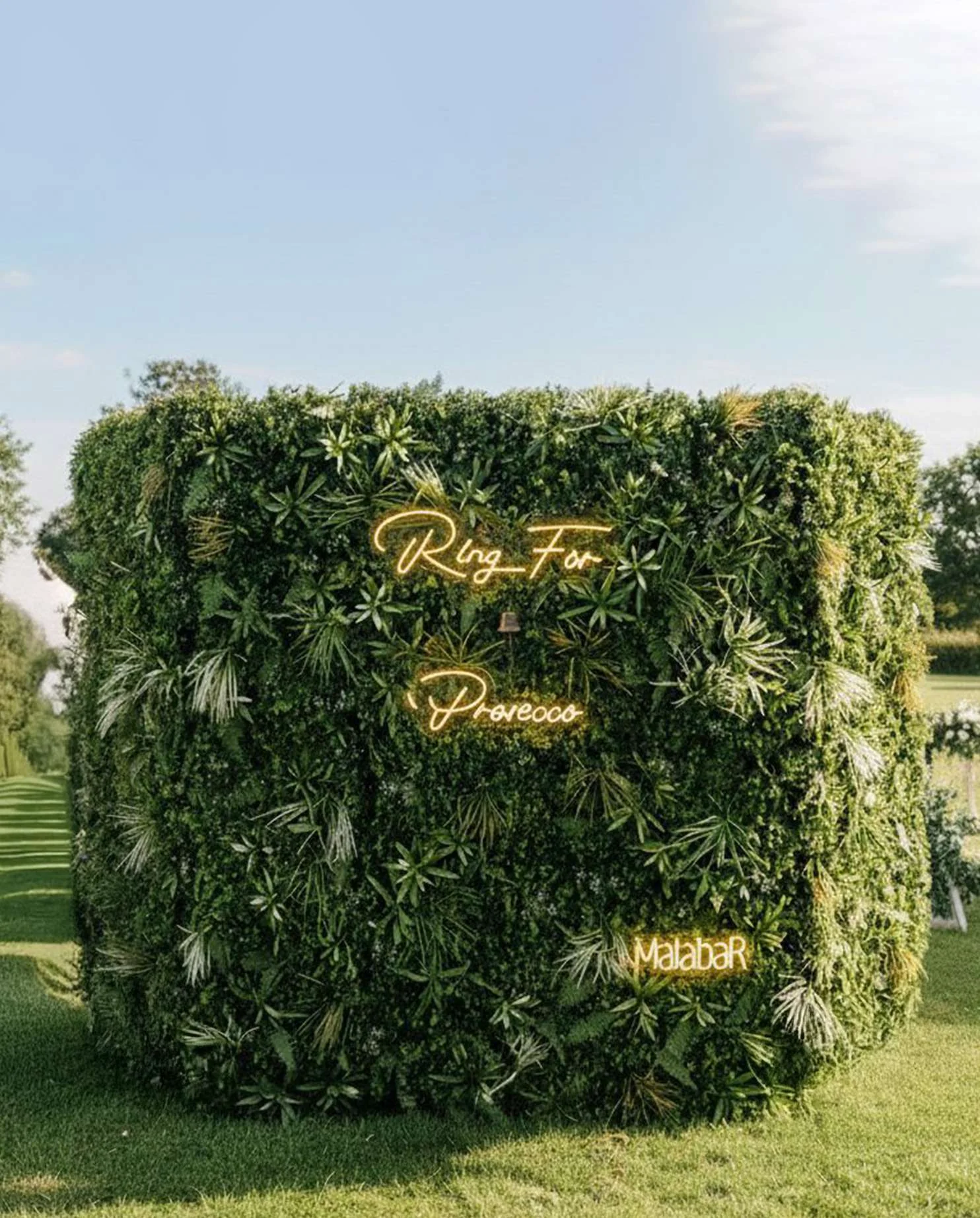 The Le Vert welcome station: a foliage-covered Prosecco wall on a garden lawn